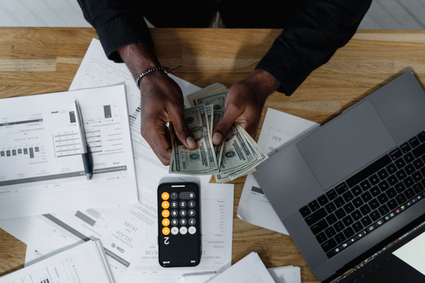 Counting US dollars alongside a calculator and financial documents